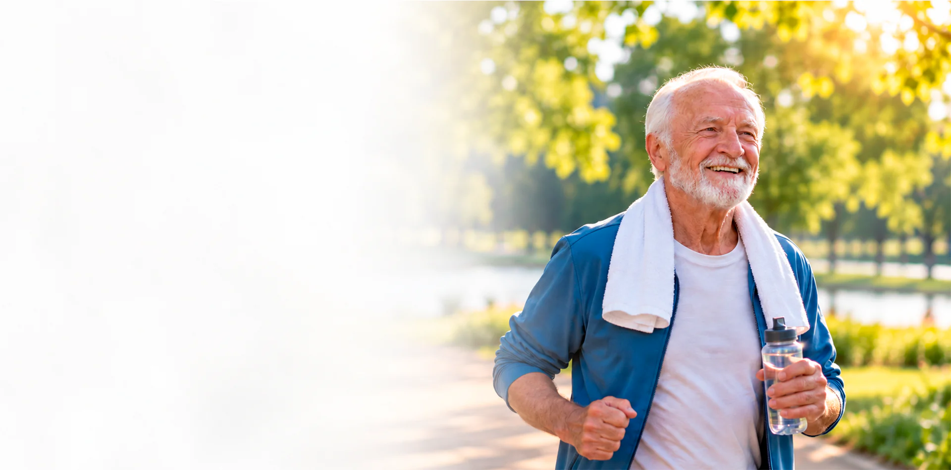 Homem idoso sorridente caminhando em um parque, com uma toalha no pescoço e uma garrafa de água